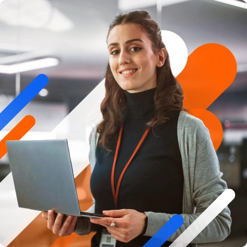 A woman smiling and holding a laptop, standing in a modern office environment with abstract geometric shapes in the background.