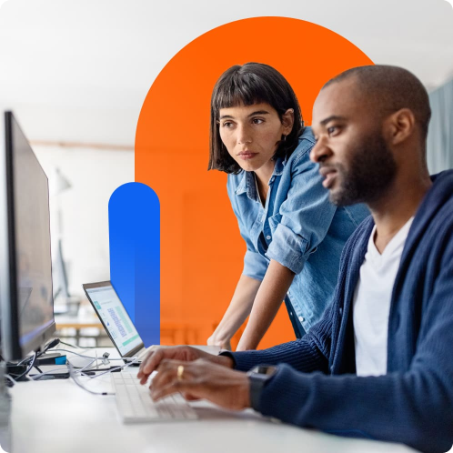 Two individuals collaborate at a desk with a computer, against an abstract orange and blue backdrop.